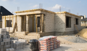 Modern Nigerian bungalow under construction with neatly laid sandcrete blocks and organised site materials on a clean compound